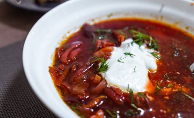 Beyaz tabakta ekşi kremayla pişirilmiş kırmızı borç.