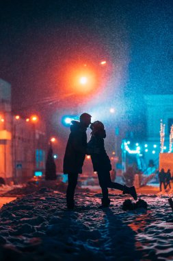 Karla kaplı sokakta kolları birbirine girmiş genç bir çift..
