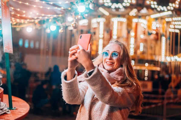 Mulher leva selfie no desfoque luz de fundo na rua à noite — Fotografia de Stock