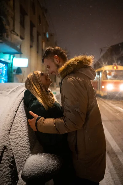Young adult couple kissing each other on snow covered street — Stock Photo, Image