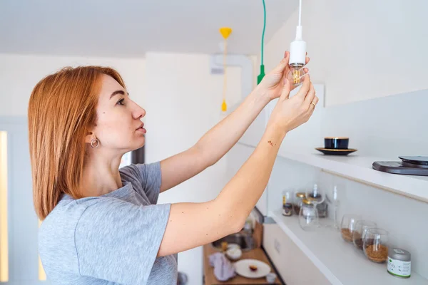 Frau schraubt Glühbirne auf Licht leuchtet nicht — Stockfoto