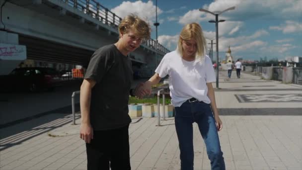 The guy is teaching his girlfriend to skateboard. Date of hipsters. — Stock Video