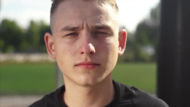 Молодой спортивный красавчик в черной рубашке смотрит в камеру — стоковое видео