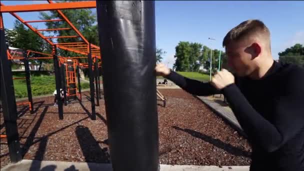 Boxeador de entrenamiento con saco de boxeo al aire libre . — Vídeo de stock