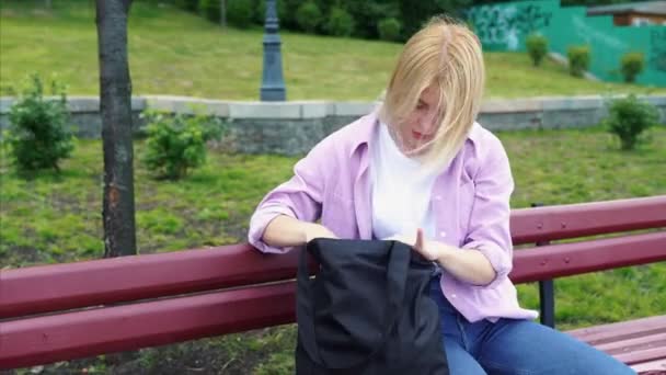 Hermosa joven mujer mirando dentro de su bolso — Vídeos de Stock