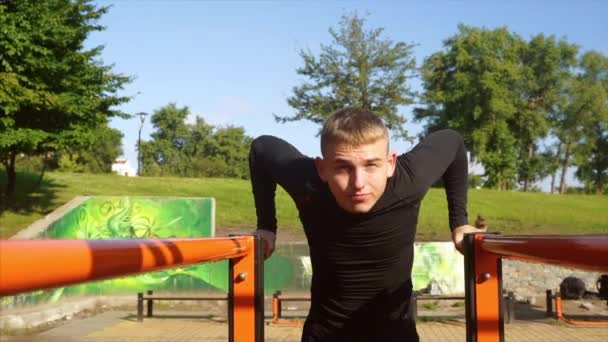 Jonge sterke man doet de oefeningen op de ongelijke bars — Stockvideo