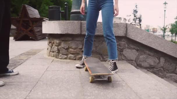 The guy is teaching his girlfriend to skateboard. Date of hipsters. — Stock Video