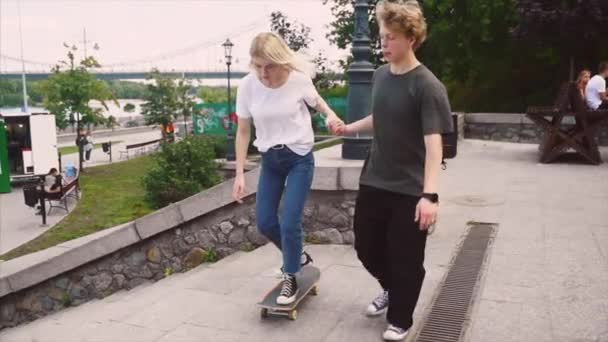 Парень учит свою девушку кататься на скейтборде. Дата хипстеров . — стоковое видео
