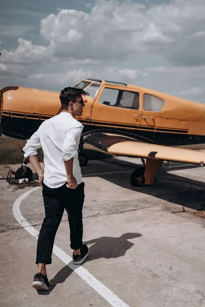 Ένας άνθρωπος στέκεται στο φόντο ενός μικρού μονοκινητήριου αεροπλάνου. — Φωτογραφία Αρχείου
