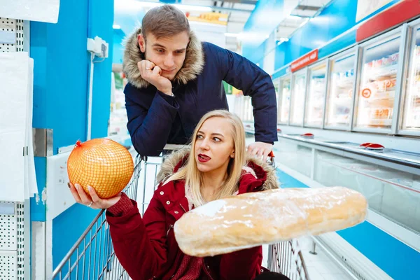Молодий красивий хлопець їде дівчину в супермаркеті на візку — стокове фото