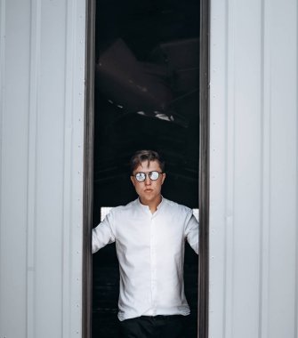 Güneş gözlüklü yakışıklı bir adam hangarın kapısını açıyor..