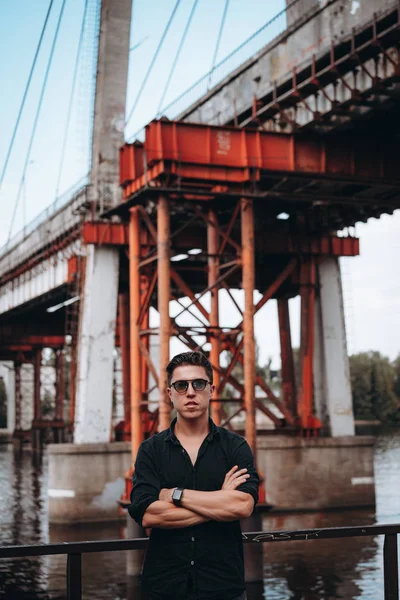 Guy i solglasögon på bakgrunden av bron — Stockfoto