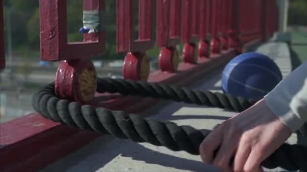 Mains féminines tirant une corde à travers une clôture sur un pont — Video