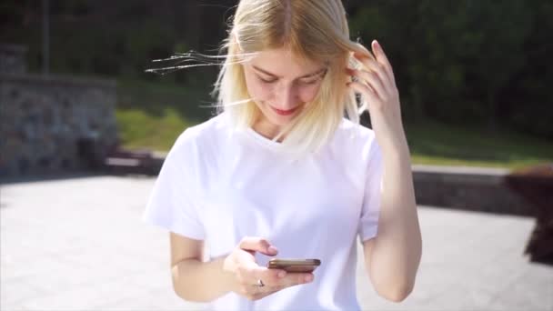 Sokakta gülümseyen bir kızın portresi akıllı telefon kullanıyor.. — Stok video