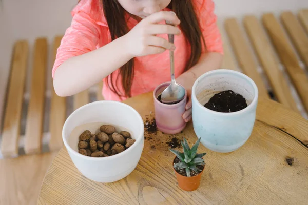 Bambina scava il terreno per roset con un cucchiaio — Foto Stock