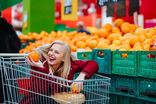 Jolie jeune femme hipster assise dans un chariot de supermarché au supermarché — Photo
