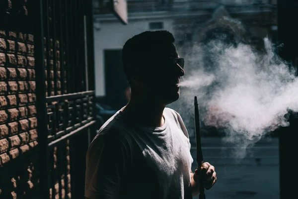 Silhouette del produttore di narghilè che soffia fumo al buio . — Foto Stock