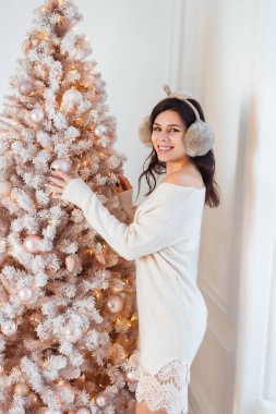 Noel ağacının yanında zarif elbiseli genç bir kadın.