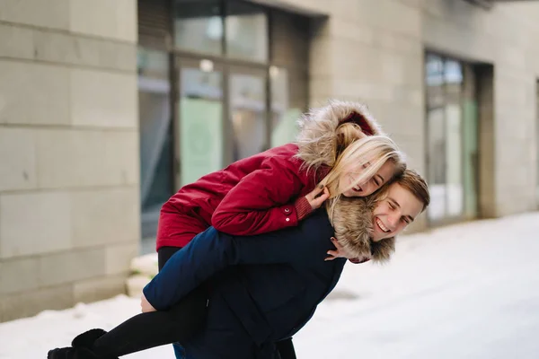 Mladý pohledný chlap dávat dívkafirend piggyback jízda — Stock fotografie