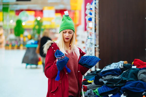 Νεαρή γυναίκα επιλέγει καπέλο στο εμπορικό κέντρο — Φωτογραφία Αρχείου