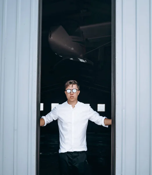 En stilig kille i solglasögon öppnar dörren till hangaren.. — Stockfoto