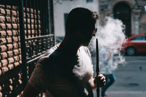 Silhueta de fabricante de narguilé soprando fumaça no escuro . — Fotografia de Stock