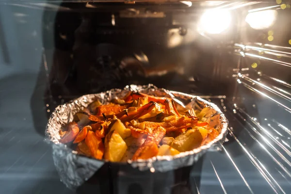 Batatas assadas com cenoura e outras especiarias na assadeira. — Fotografia de Stock