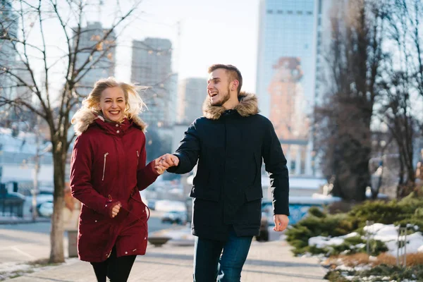 Pareja feliz caminando en la calle en invierno en una ciudad — Foto de Stock