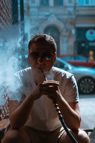 Silhuett av hookah maker blåser rök i mörkret. — Stockfoto