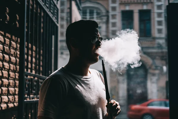 Silueta del fabricante de narguile soplando humo en la oscuridad . — Foto de Stock