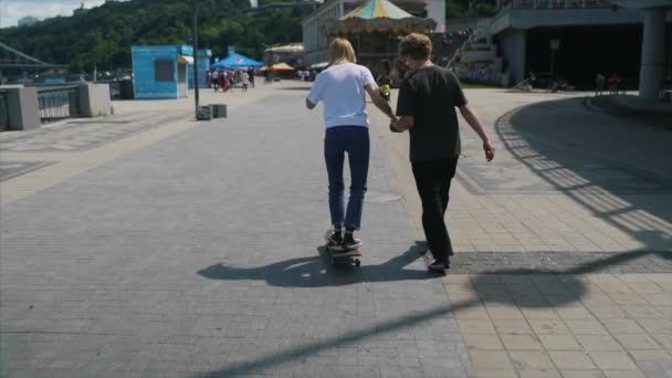 Парень учит свою девушку кататься на скейтборде. Дата хипстеров . — стоковое видео