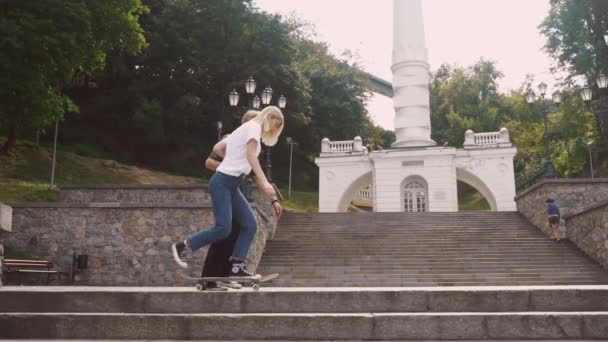 El tipo está enseñando a su novia a patinar. Fecha de los hipsters . — Vídeo de stock