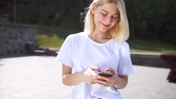 Retrato de una chica sonriente en la calle utiliza smartphone . — Vídeo de stock