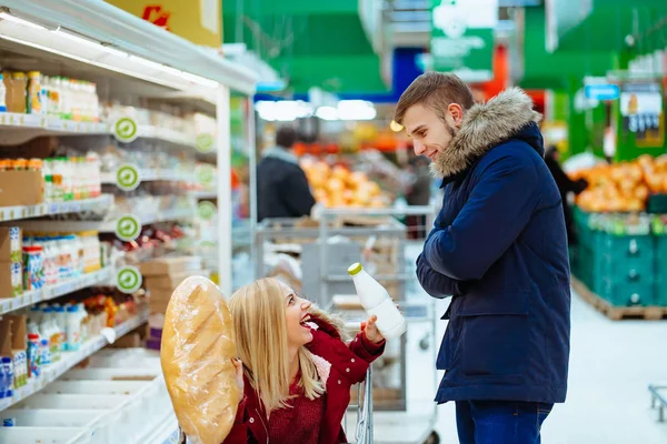 Ένας όμορφος νεαρός καβαλάει ένα κορίτσι σε ένα σούπερ μάρκετ με τρόλεϊ. — Φωτογραφία Αρχείου