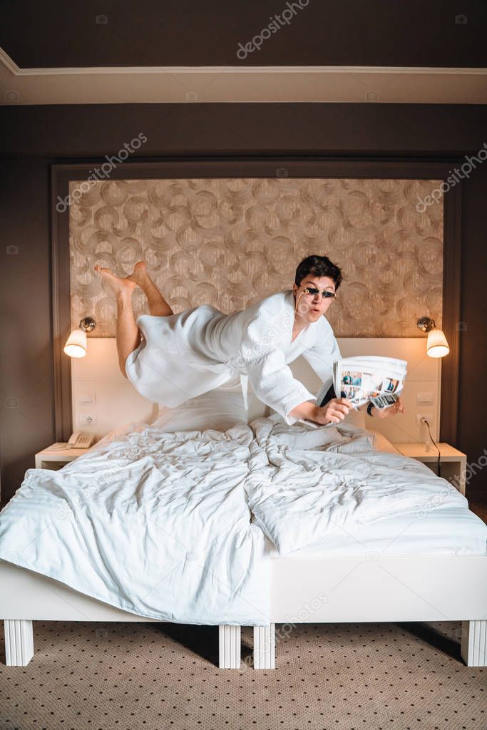 Guy with sunglasses and newspaper high in air.
