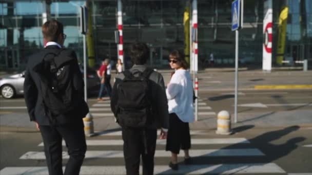 Два бизнесмена и женщина переходят дорогу — стоковое видео