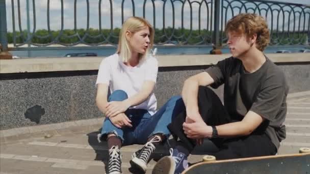 Guy and girl are sitting on the street and talking — Stock Video