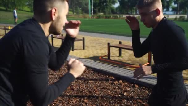 Двоє дорослих хлопців займаються спортом, виконуючи вуличні тренування — стокове відео