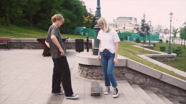 O tipo está a ensinar a namorada a andar de skate. Data dos hipsters . — Vídeo de Stock