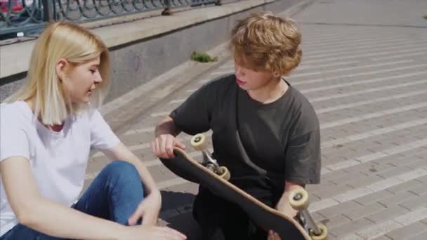 Chico y chica están sentados en la calle y hablando — Vídeos de Stock