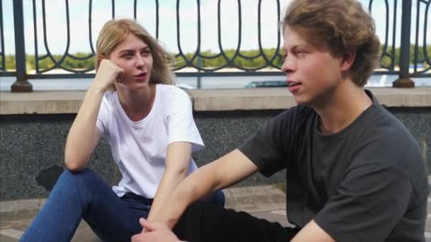 Guy et fille sont assis dans la rue et parlent — Video