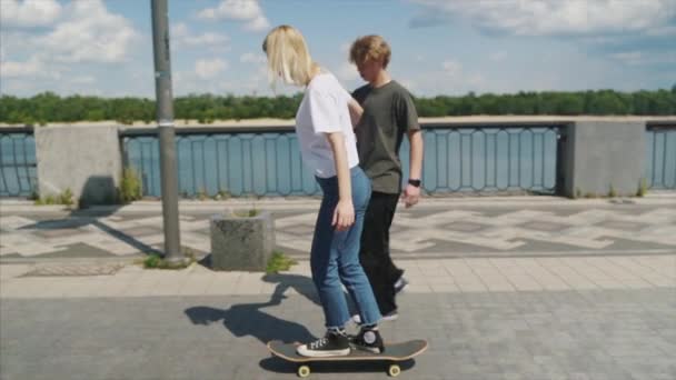 O tipo está a ensinar a namorada a andar de skate. Data dos hipsters . — Vídeo de Stock