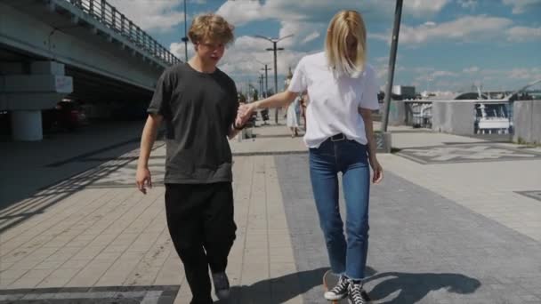 The guy is teaching his girlfriend to skateboard. Date of hipsters. — Stock Video