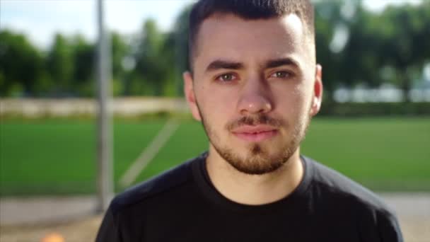 Jovem desportivo bonito homem modelo em camisa preta olhando para a câmera — Vídeo de Stock