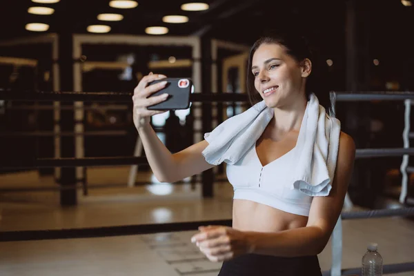 Fiatal sportos nő vesz egy selfie, a szociális hálózatok mobil telefon, tornaterem. — Stock Fotó