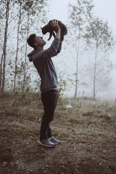 O tipo tem um gato no parque. O parque está envolto em nevoeiro — Fotografia de Stock