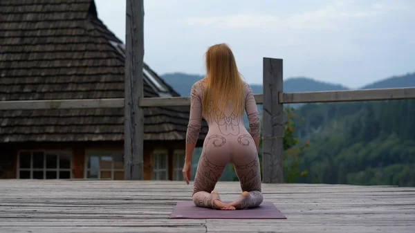 Uma mulher pratica ioga pela manhã em um terraço ao ar livre . — Fotografia de Stock