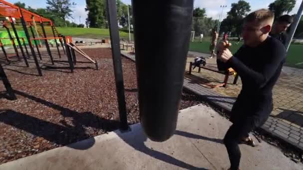 Boxeador de entrenamiento con saco de boxeo al aire libre . — Vídeos de Stock