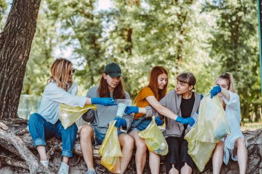 Bir grup aktivist arkadaş parkta plastik atık topluyor. Çevresel koruma.