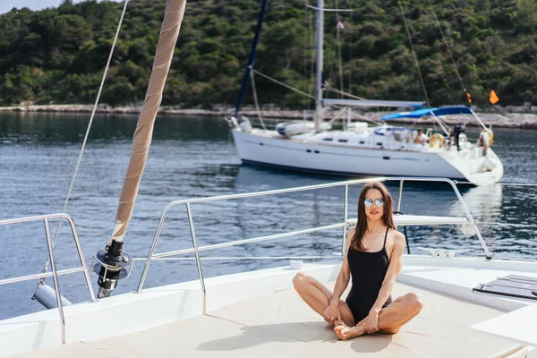 Mujer joven sana y tranquila haciendo yoga en yate de vela en el mar en el fondo de la isla —  Fotos de Stock